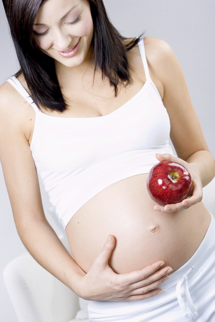 Glückliche schwangere Frau mit Apfel in der Hand