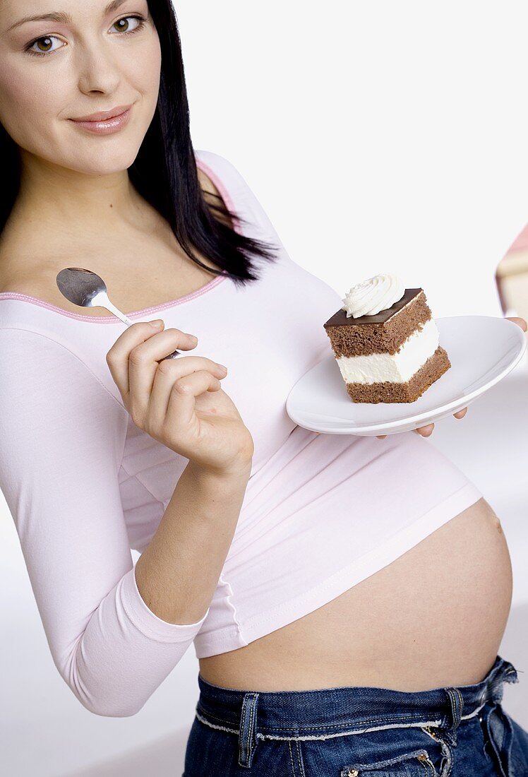 Pregnant woman, holding a plate with a piece of cake