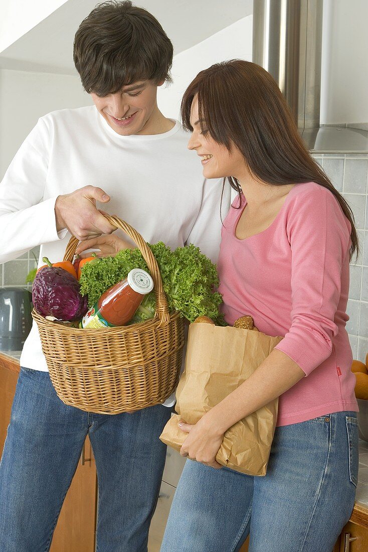 Young couple standing in kitchen with shopping