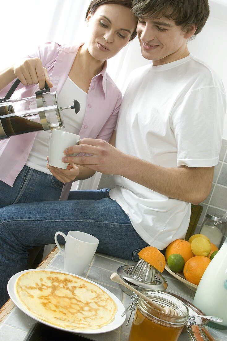 Junges Paar in der Küche, Frau schenkt Kaffee ein