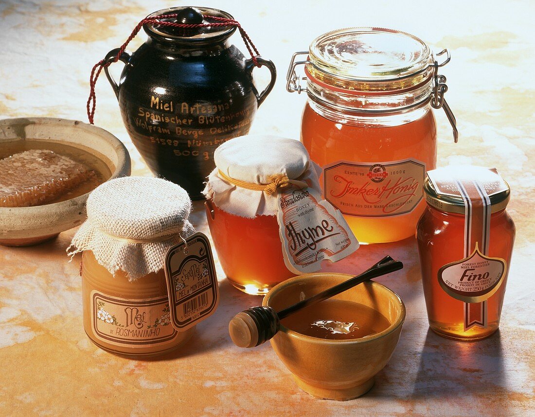Mehrere Honigläser und Schüssel mit Honig
