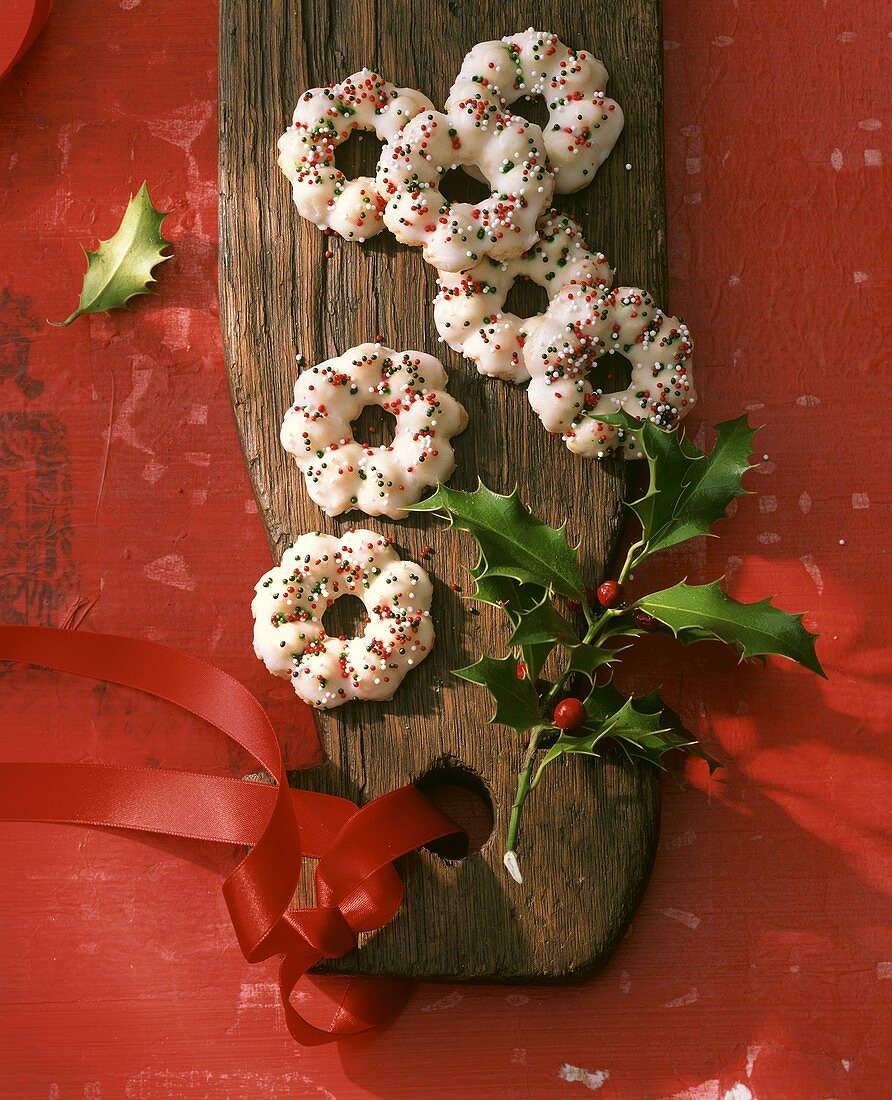 Almond biscuits on a wooden platter with sprig of holly