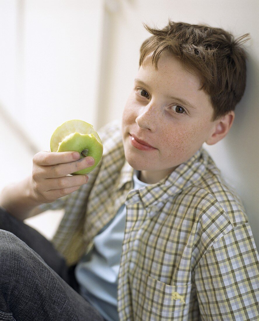 Junge hält angebissenen Apfel in der Hand