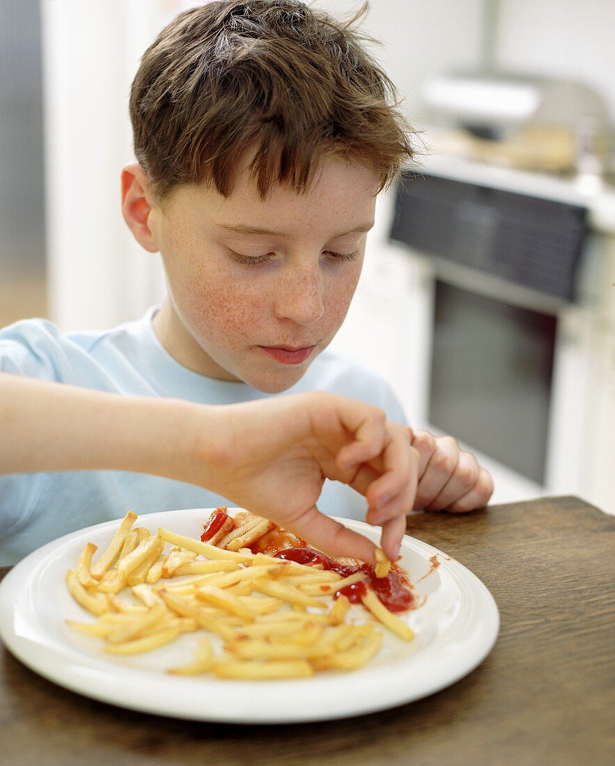 Boy dipping chips into ketchup