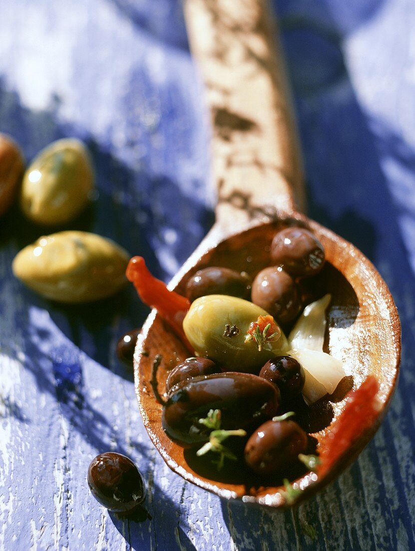Assorted marinated olives on a wooden spoon