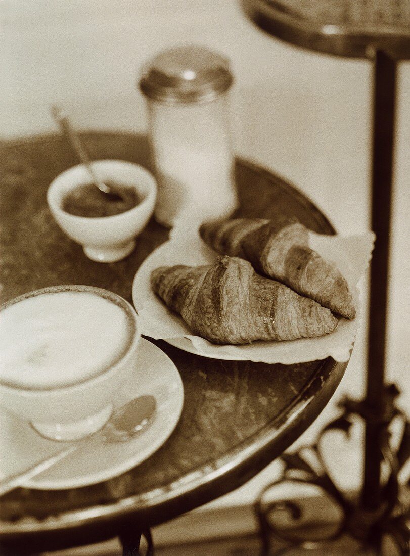 Bistrotisch mit Café au lait, Croissants und Marmelade