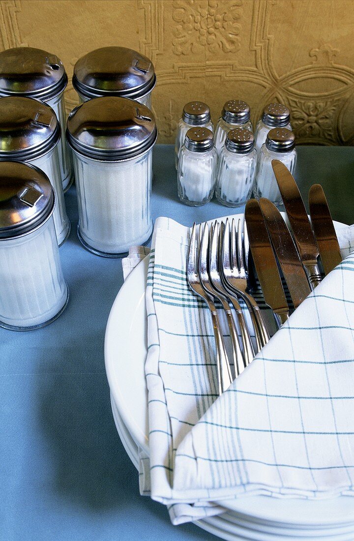 Cutlery in kitchen cloth, sugar shakers and salt shakers