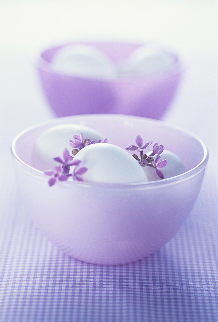Two purple bowls with white eggs and lilac