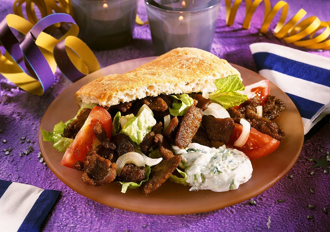 Pfannengyros mit Salat und Tzatsiki im Fladenbrot auf Teller