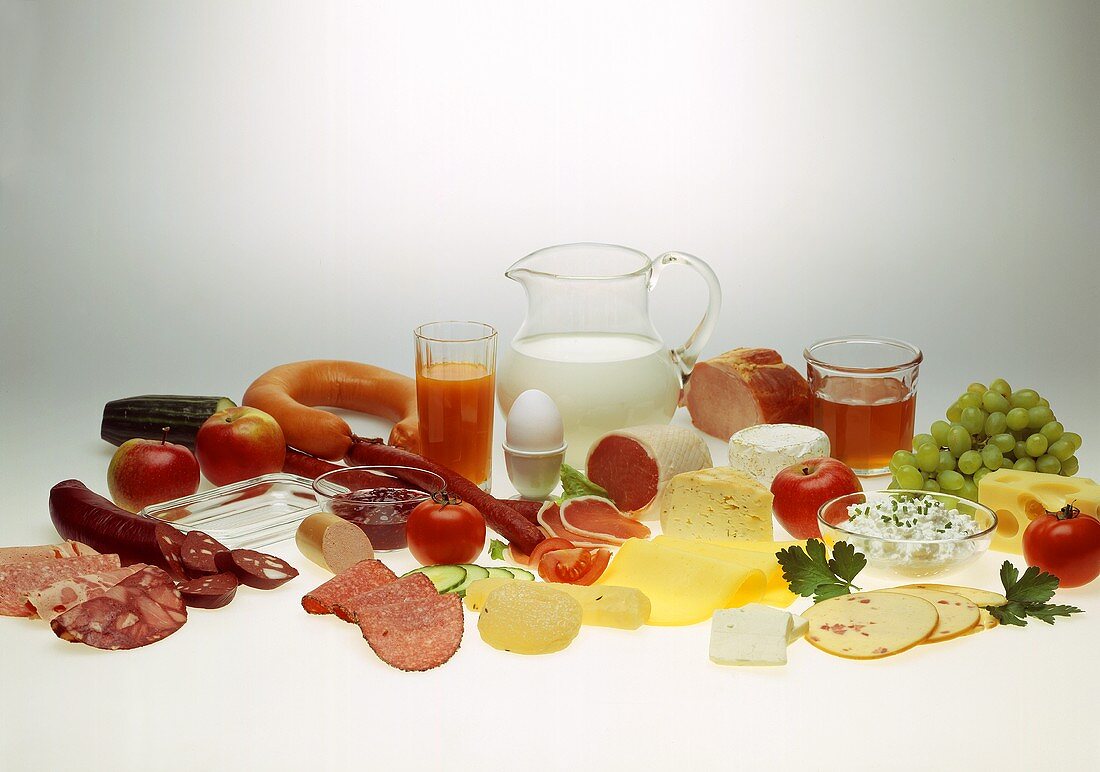 Still life with sausage, cheese, egg, milk, jam, fruit