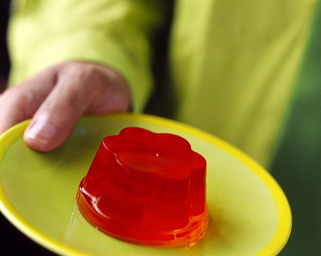 Hand holding plate of red jelly