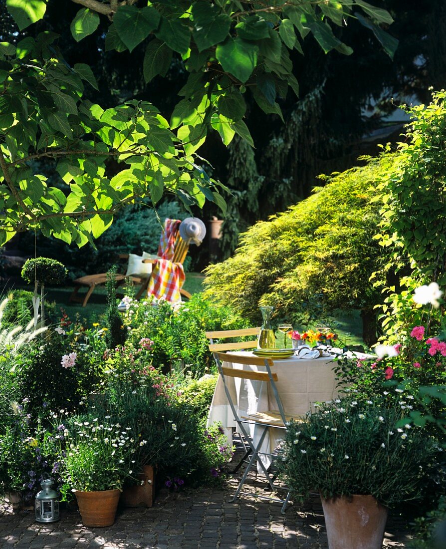 Blick in Garten mit gedecktem Gartentisch, hinten: Liegestuhl