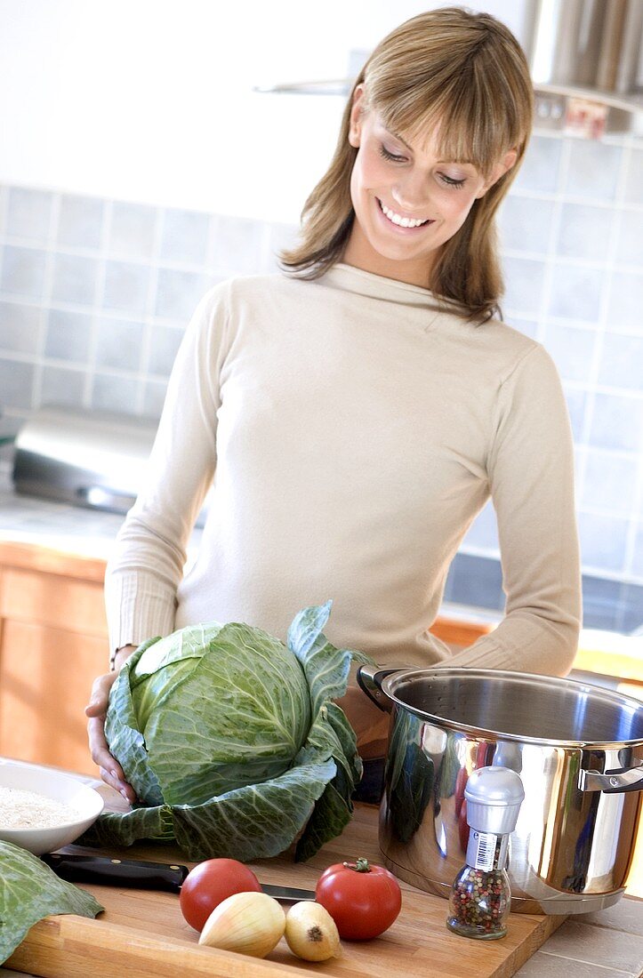 Young woman with vegetables and pan in kitchen