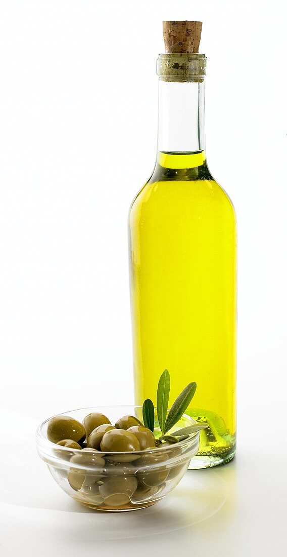 Ein Schälchen grüne Oliven und Flasche Olivenöl