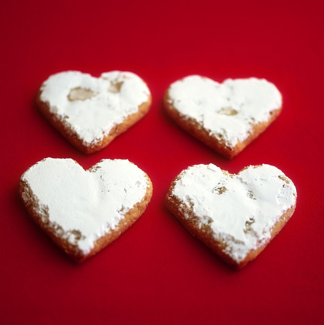Four heart-shaped almond biscuits with icing sugar