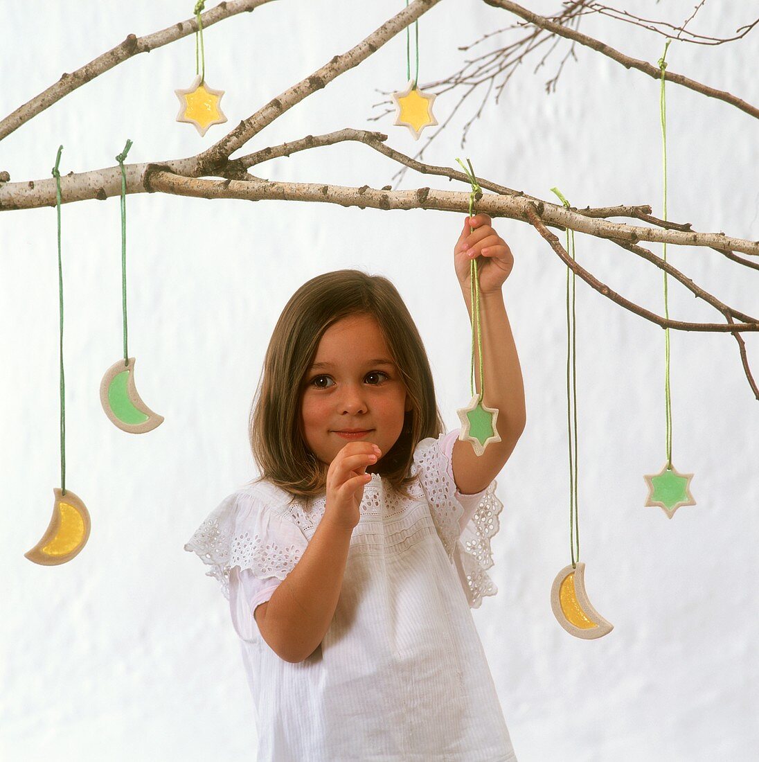 Small girl under birch branch with Christmas tree ornaments