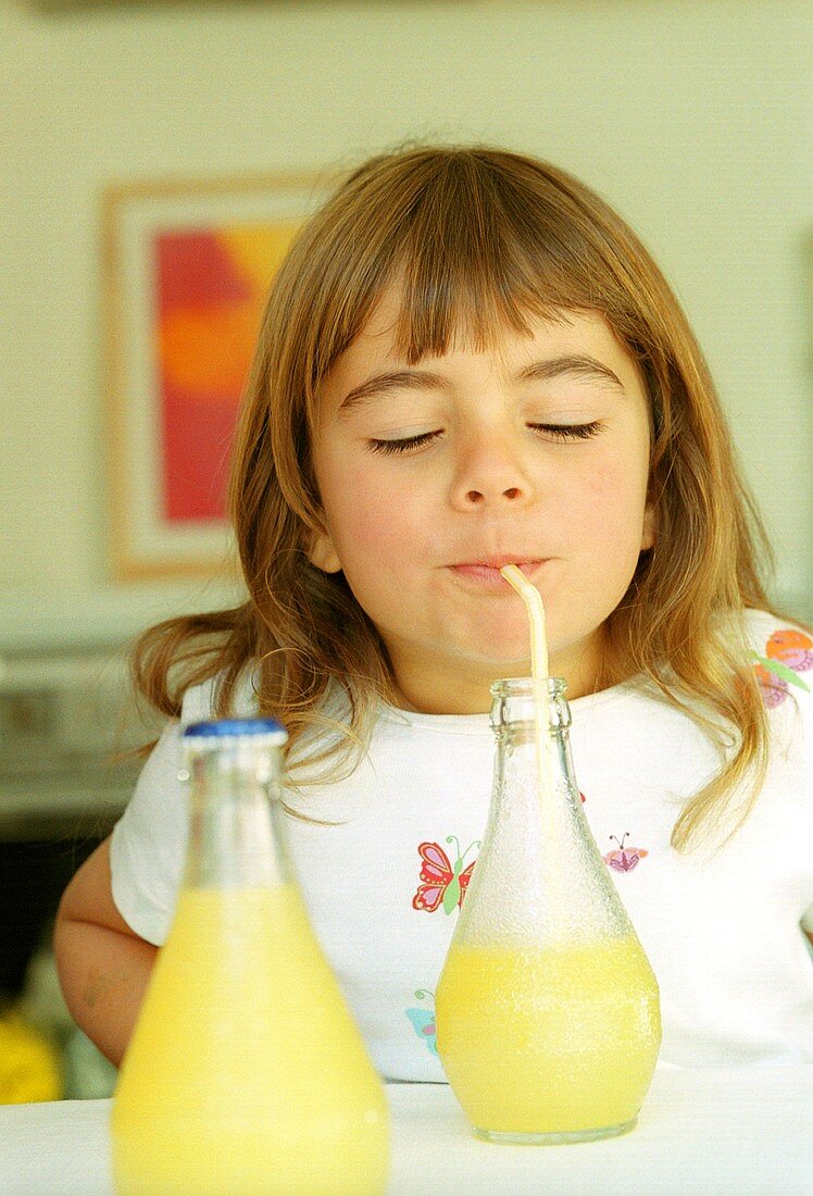 Kleines Mädchen trinkt Orangenlimonade