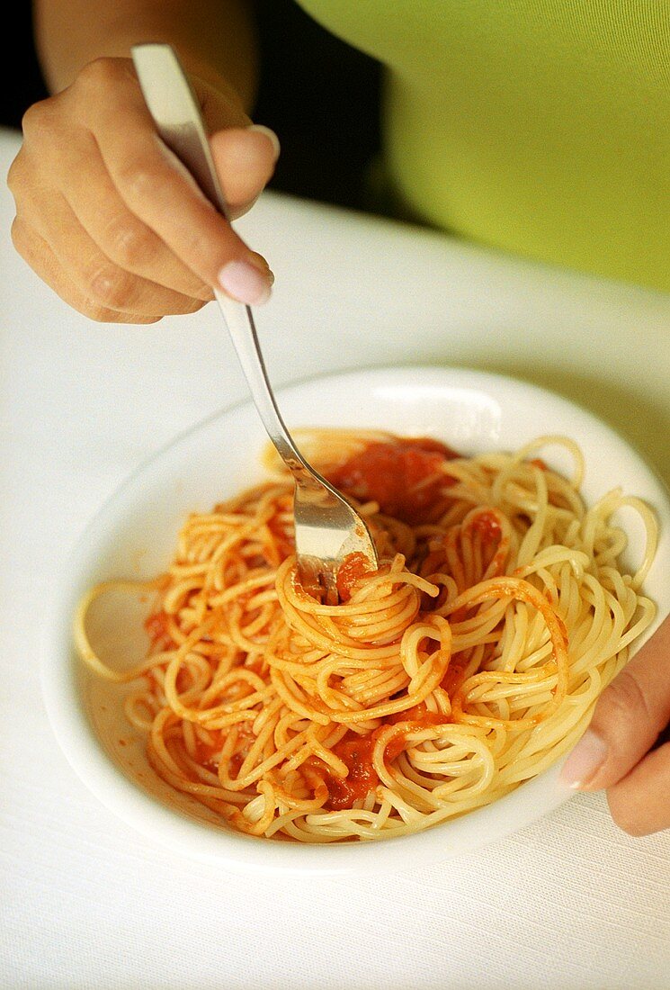 Spaghetti mit Tomatensauce auf Gabel drehen