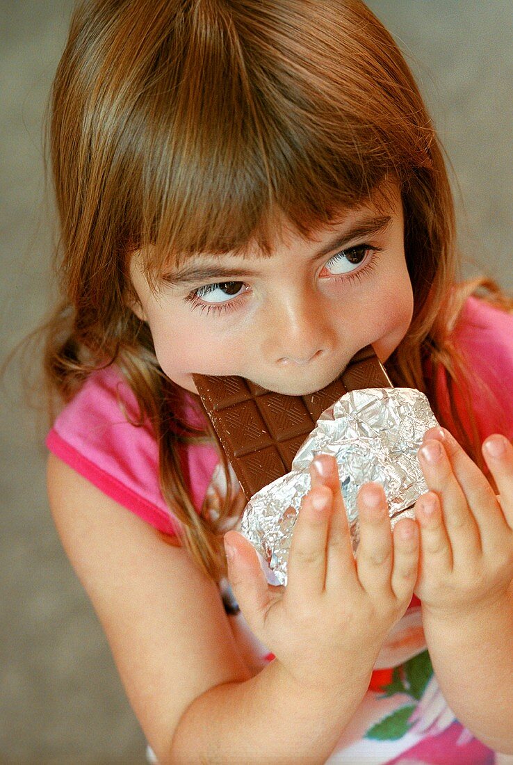 Mädchen beisst in Schokoladentafel