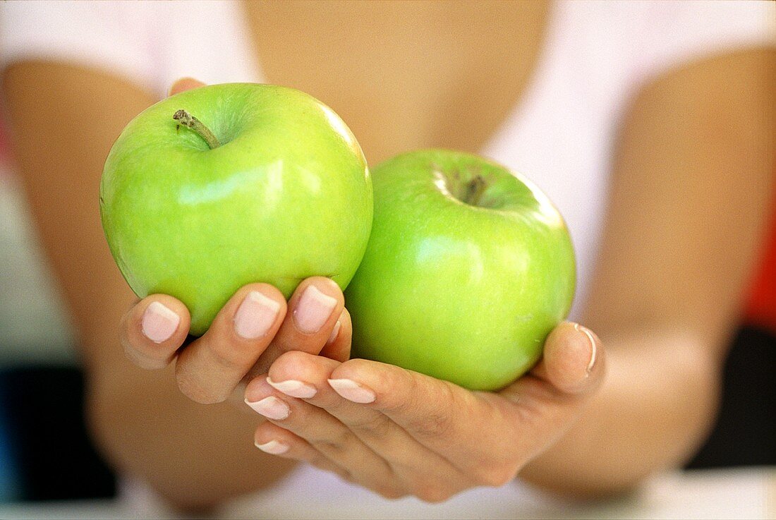 Hands holding two Granny Smith apples