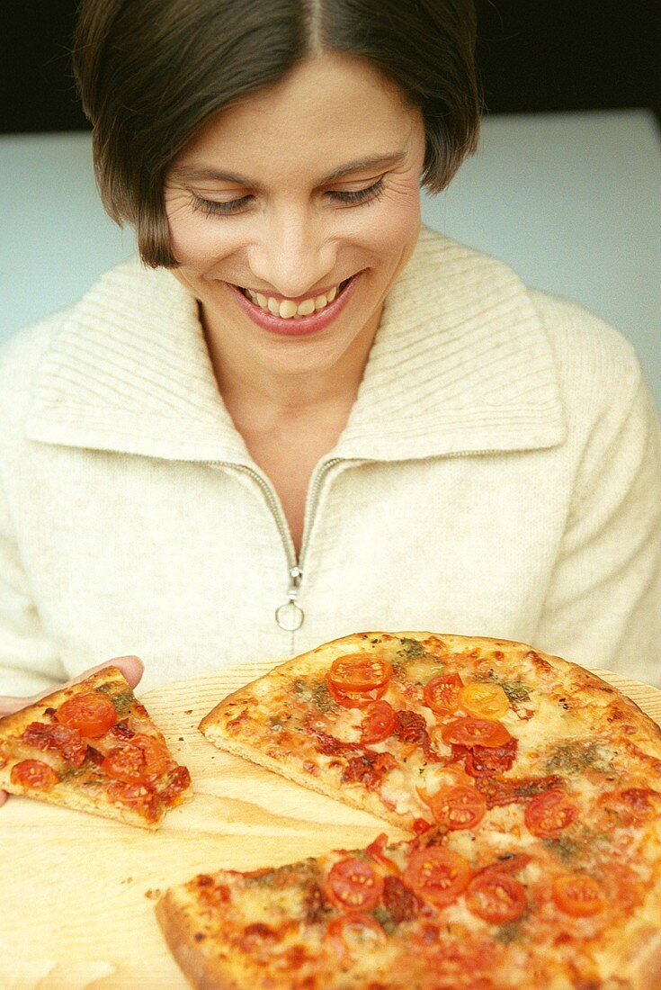 Young woman in front of pizza with a piece cut (grainy effect)