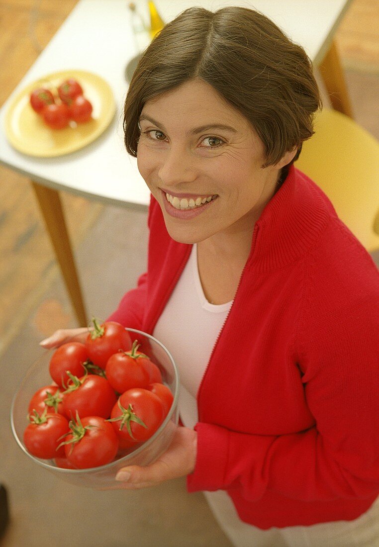 Woman holding dish of tomatoes (grainy effect)