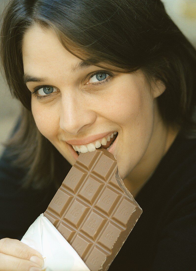 Junge Frau beisst in Tafel Schokolade