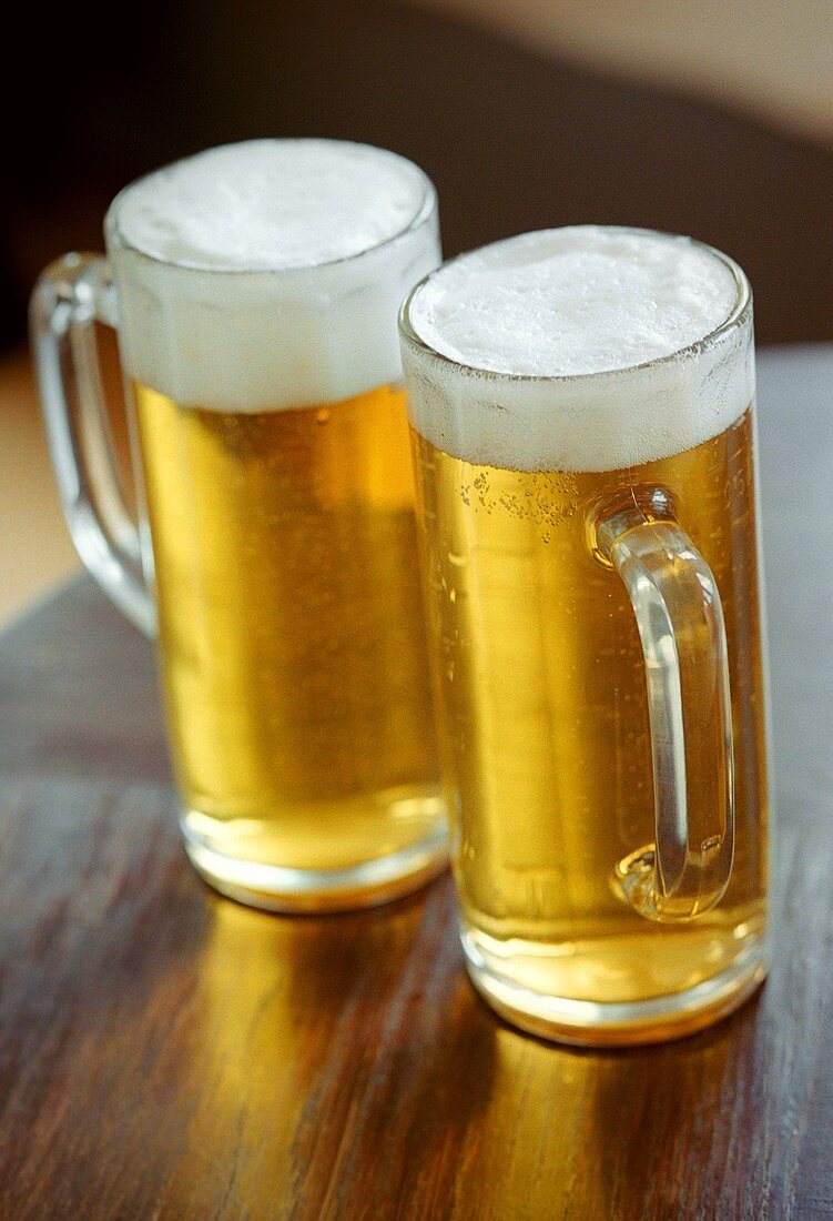 Zwei Gläser helles Bier auf Holztisch