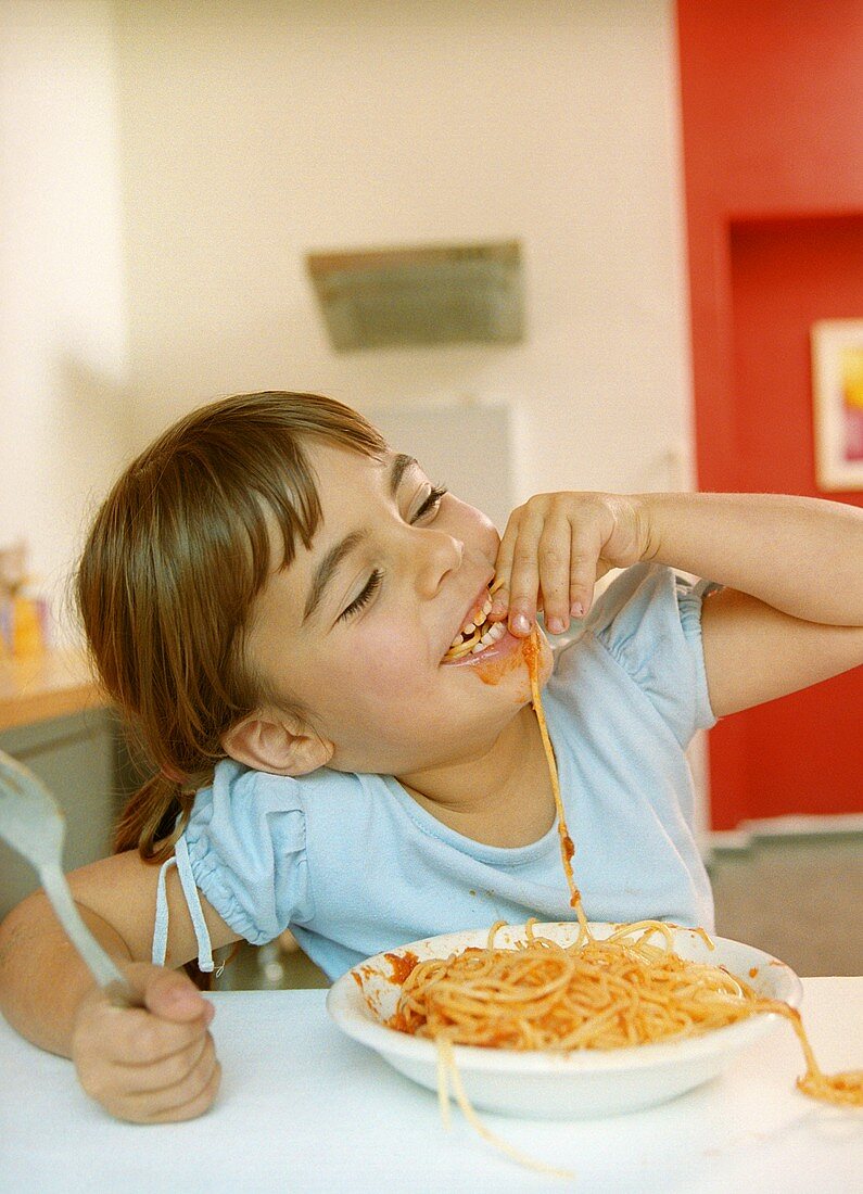 Girl eating spaghetti with tomato sauce (grainy effect)