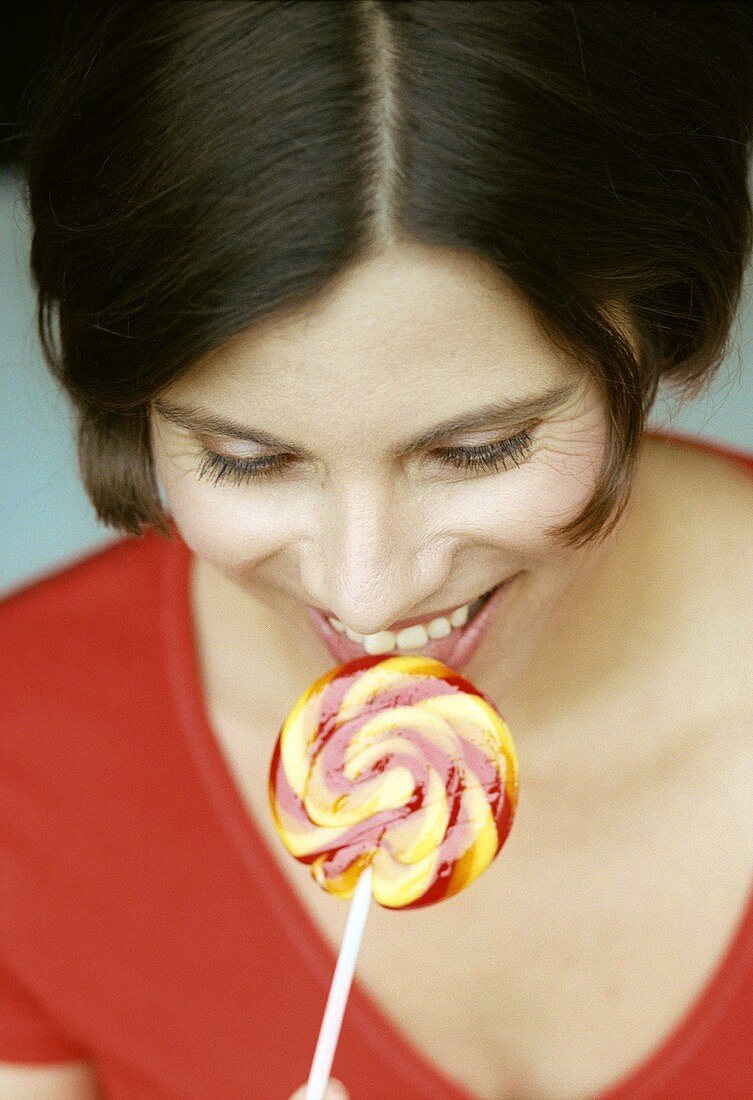 Woman eating coloured lollipop (grainy effect)