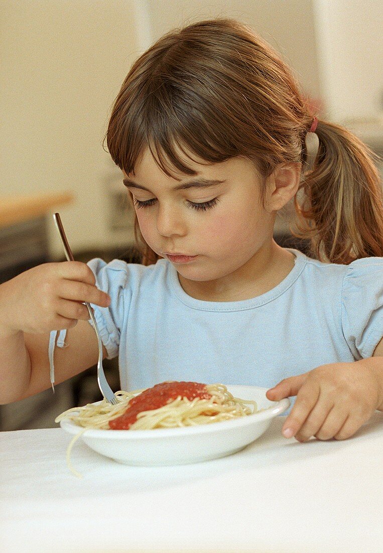Mädchen vor Teller Spaghetti mit Tomatensauce