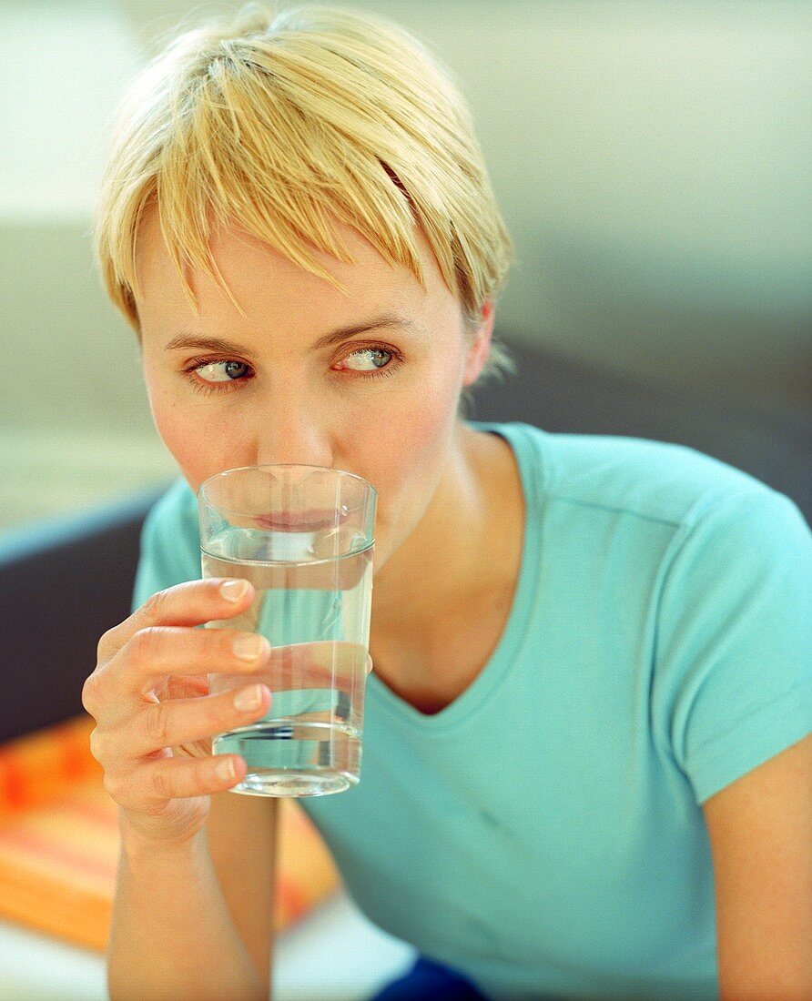 Blond woman drinking a glass of water (grainy effect)