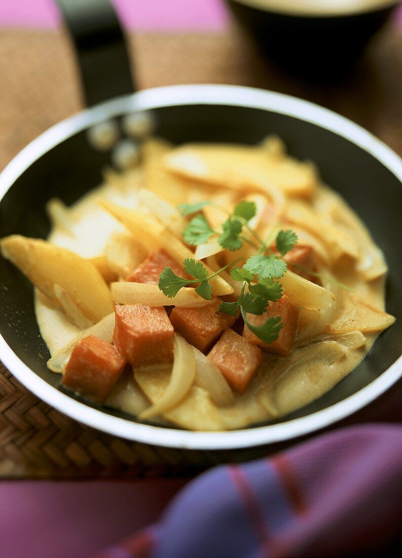 Potato and pumpkin curry with onions in a frying pan