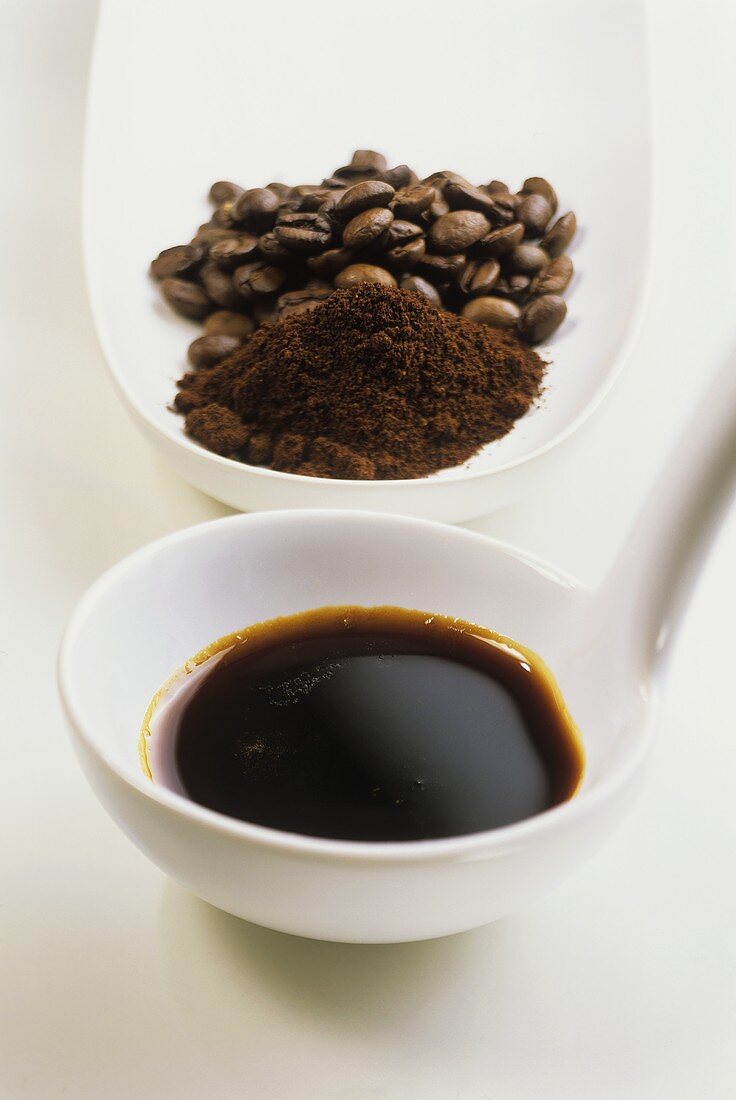 Espressosirup auf Kelle vor Kaffeepulver und -bohnen