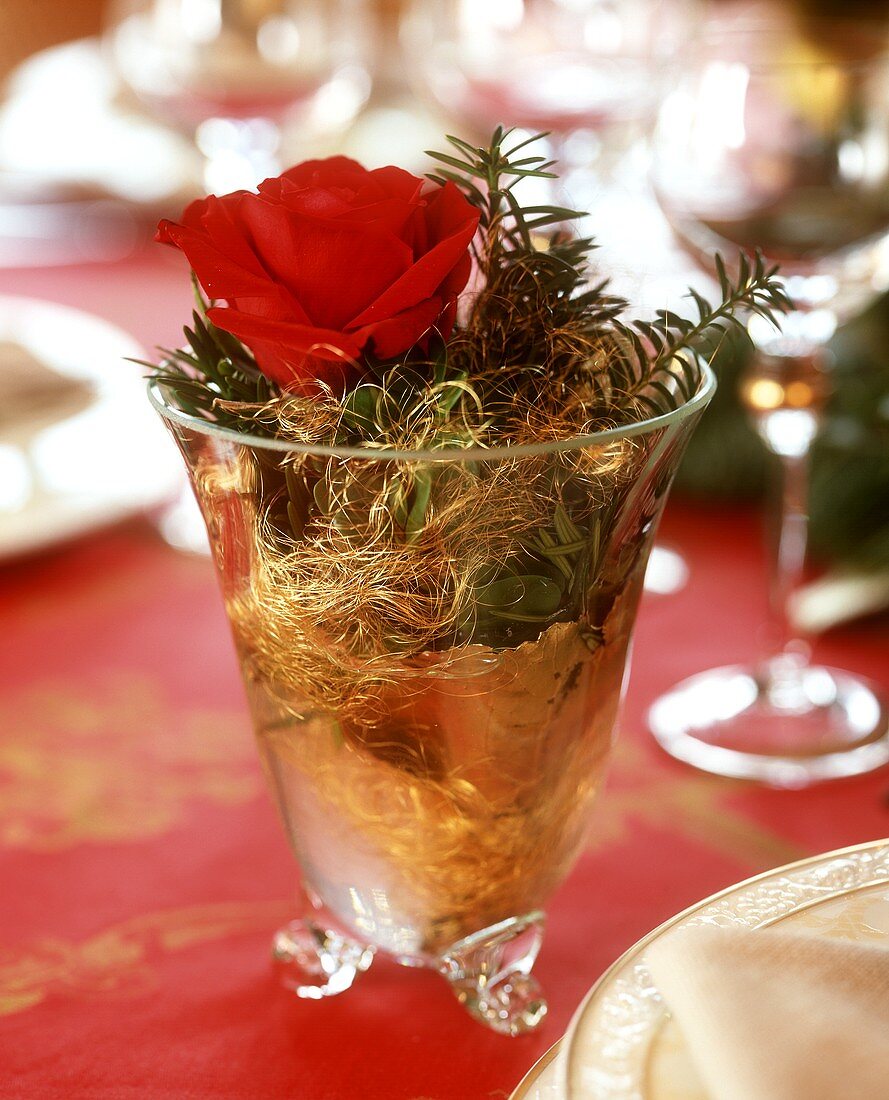 Glass decorated for Christmas with rose, fir and angel's hair