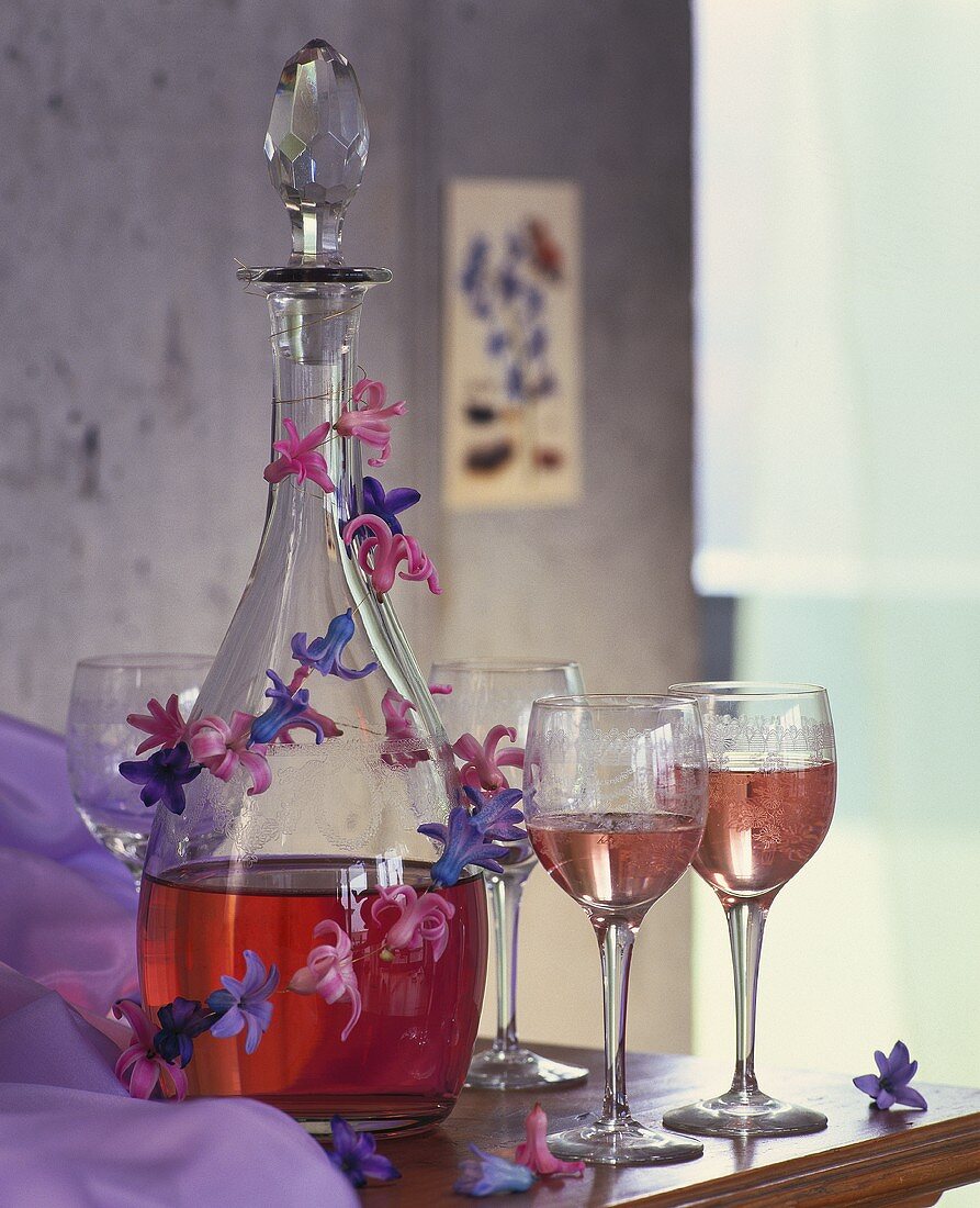 Roséwein in Glaskaraffe mit Girlande aus Hyazinthenblüten