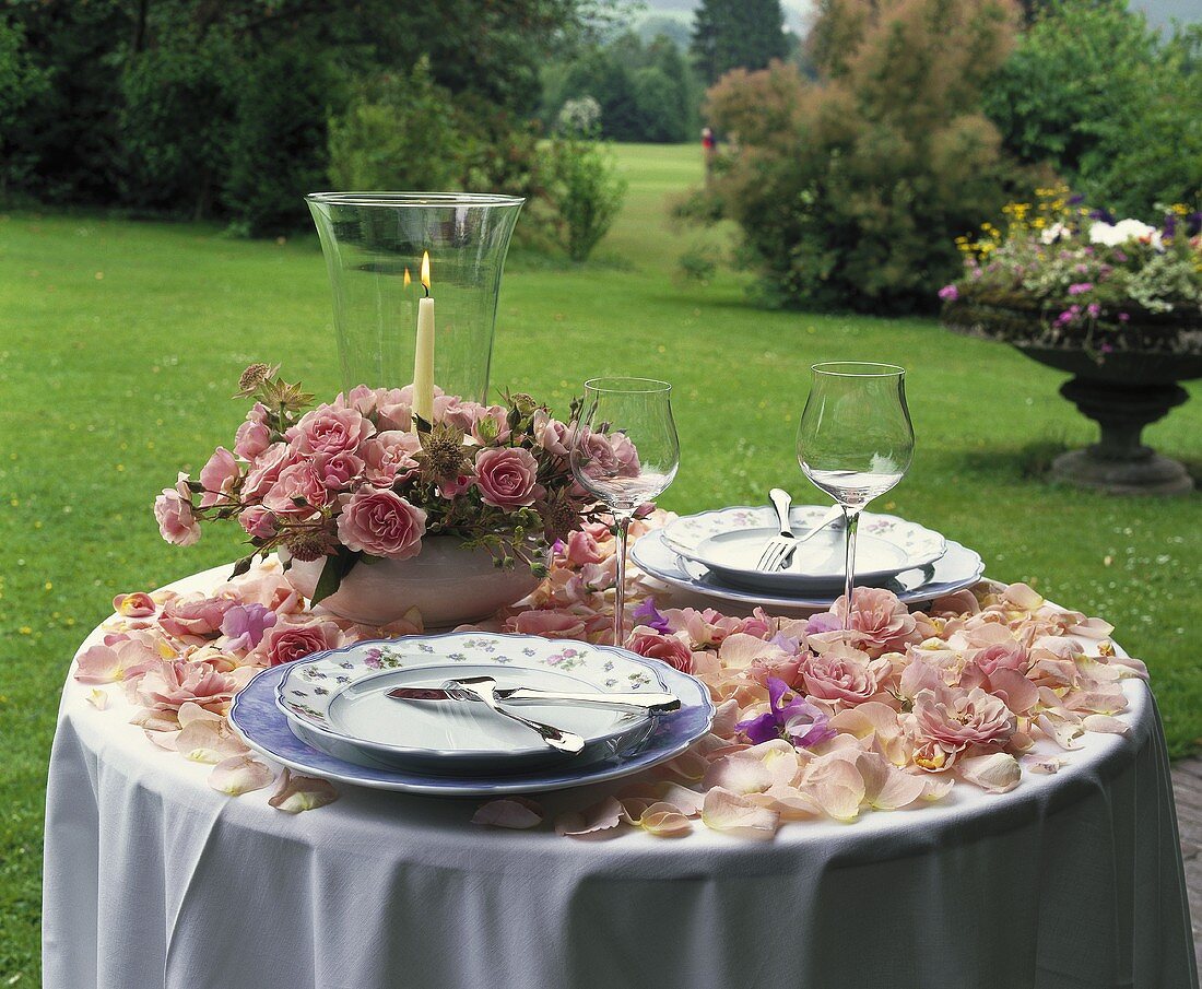 Romantischer Tisch mit Rosenblüten & Rosengesteck im Garten