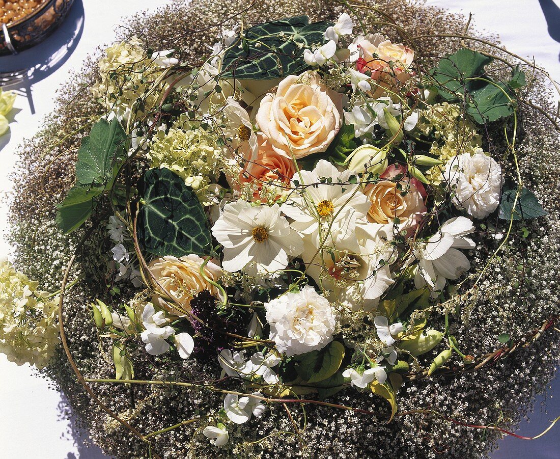 Rosen und weiße Cosmea in einem Nest aus Schleierkraut