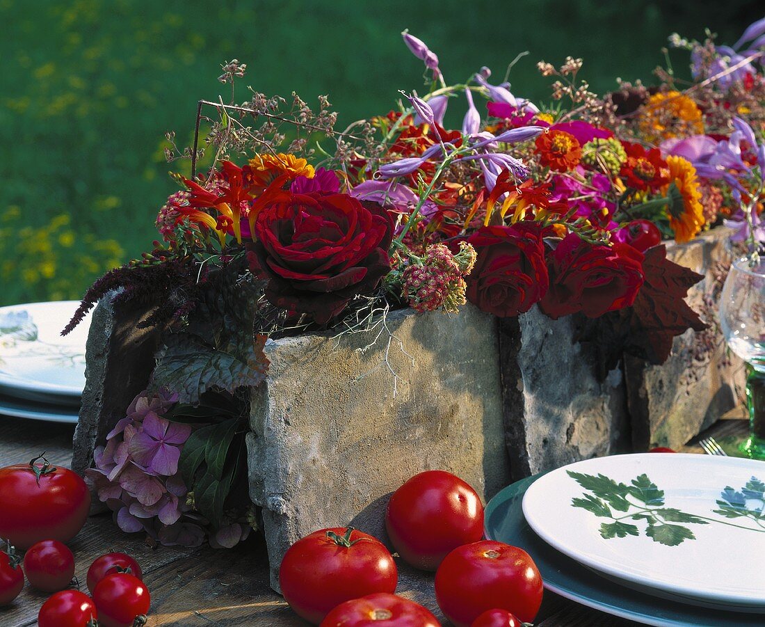 Flower arrangement in vibrant colours surrounded by tomatoes
