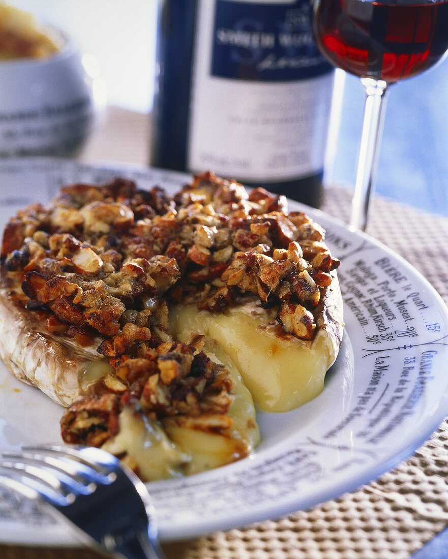 Heisser Camembert mit Nüssen, Glas Rotwein im Hintergrund