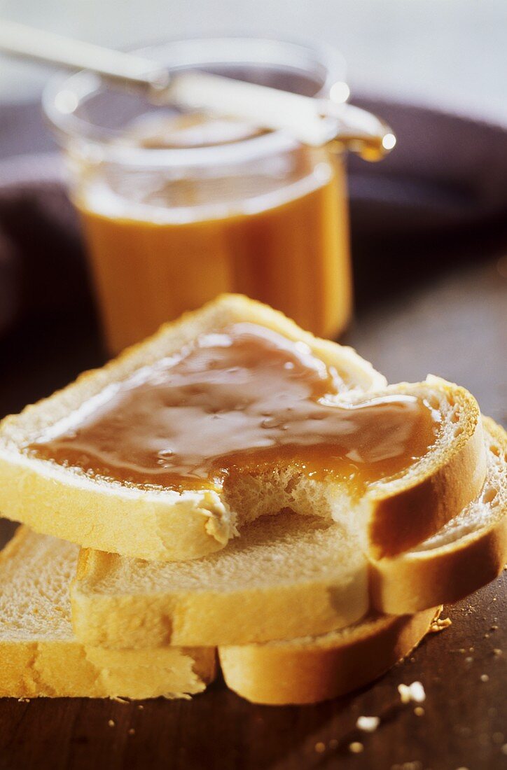 Three slices of toast, one spread with honey, a bite taken