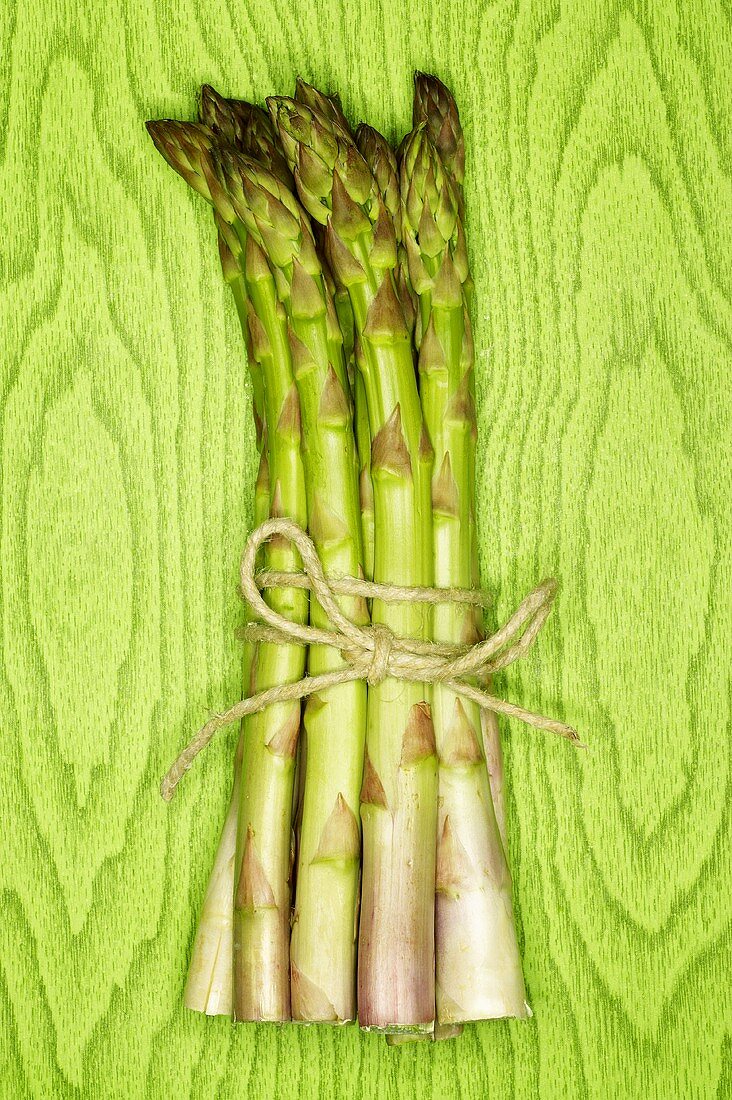 A bundle of green asparagus against green background