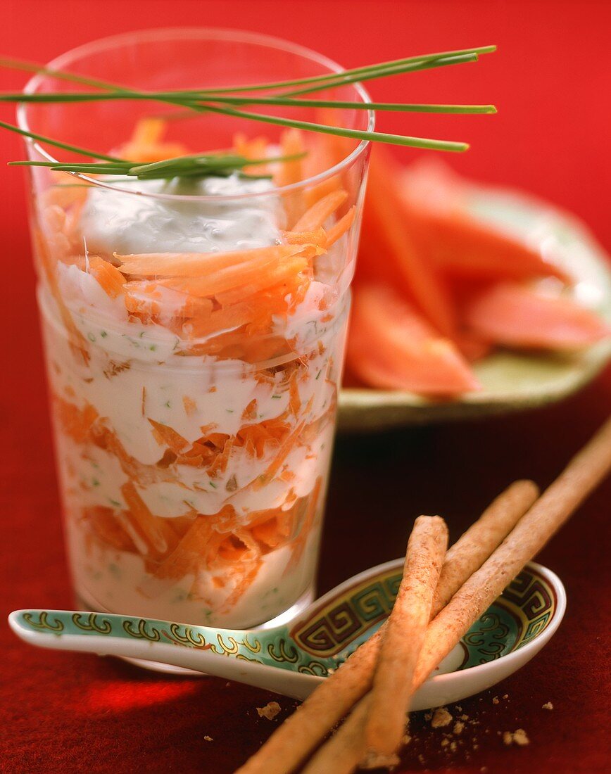 Möhren-Joghurt-Salat im Glas und Papaya im Hintergrund