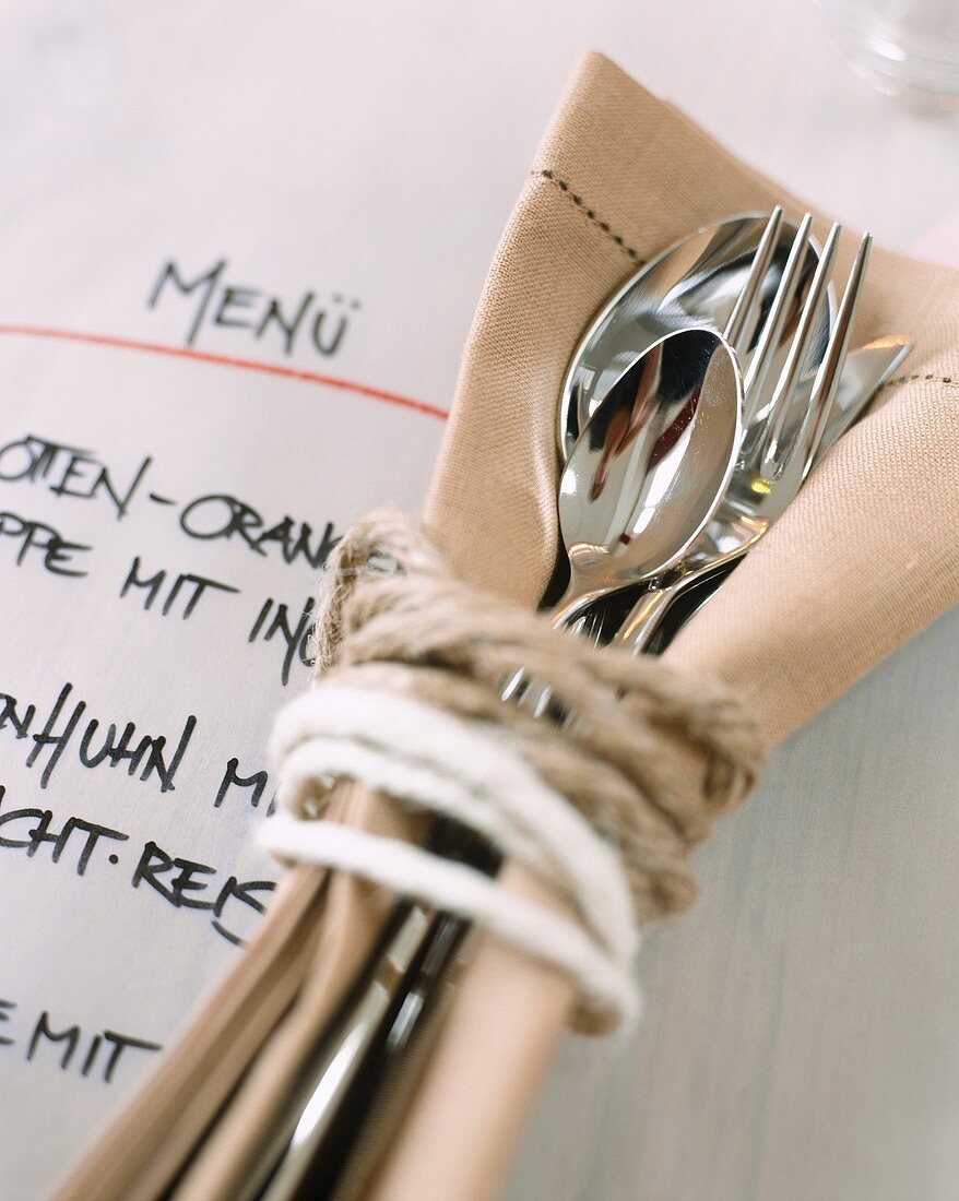 Cutlery, tied together, lying on a menu