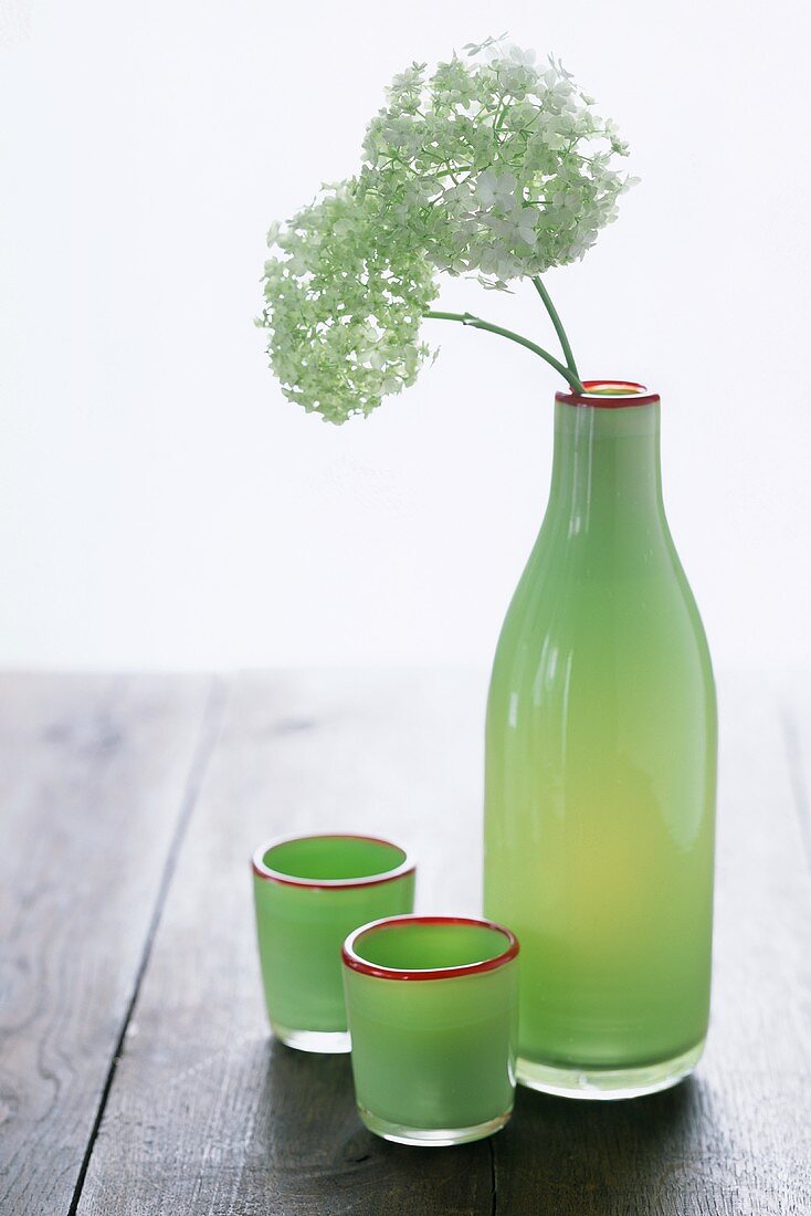 Green bottle with flowers and green glasses