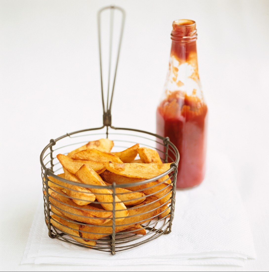 Pommes Frites in einem Körbchen mit einer Flasche Ketchup