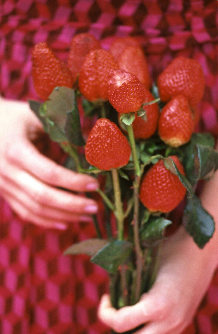 Frau hält Rosenstrauss aus Erdbeeren