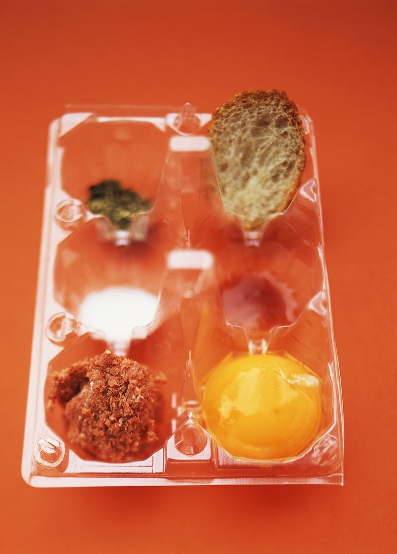 Plastic containers with corned beef, egg yolk, Tabasco & bread