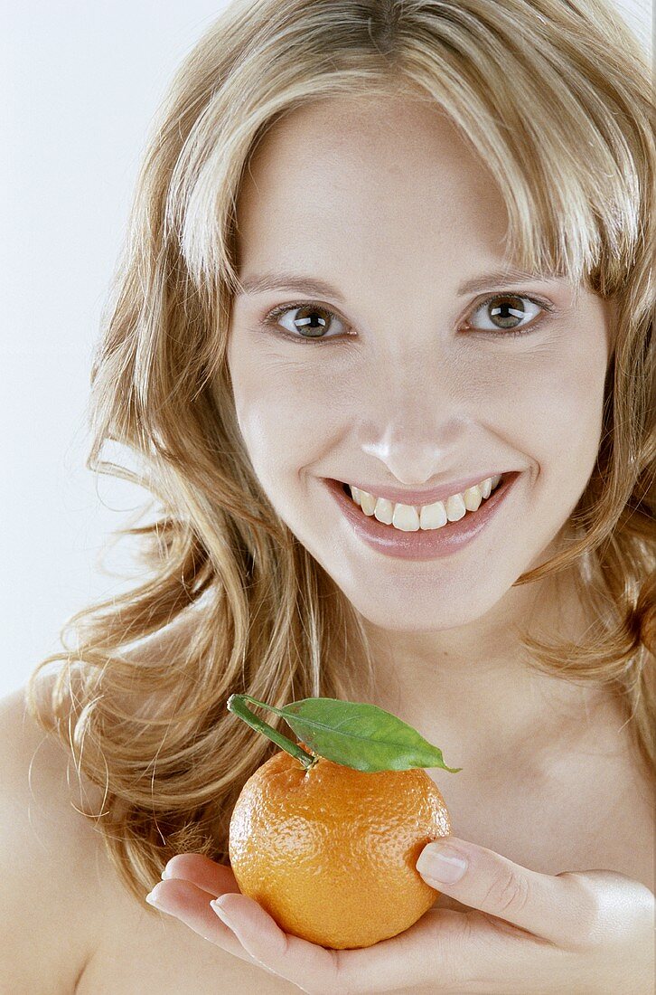 Young blond woman holding an orange in her hand