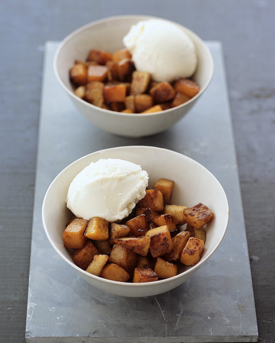 Two dishes of toasted diced pumpkin and vanilla ice cream